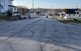 Photo shows road with cracks and uneven driving surface along Seventh Street near Seneca Street