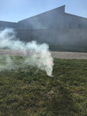 Photo of smoke coming out of a manhole in a green field outside