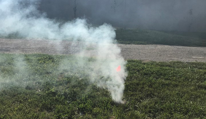 Photo of smoke coming out of a manhole in a green field outside